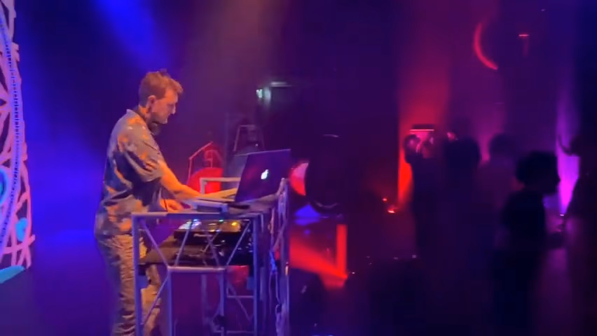 DJ Meiko Deen am Pult, atmosphärisches Licht und tanzendes Publikum im Hintergrund